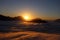 the sun at dawn with fog and backlit mountains