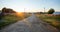 Sun-drenched ground road leading to river in village at sundown in Russia.