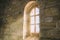 Sun-drenched window of a church with a natural stone wall