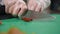 Sun dried tomatoes being sliced on a green chopping board by mans hand