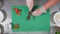 Sun dried tomatoes being sliced on a green chopping board by mans hand