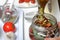 Sun-dried tomatoes with spices and garlic in a jar. Woman adds olive oil. Near rosemary, tomatoes and garlic