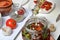 Sun-dried tomatoes with spices and garlic in a jar. Woman adds olive oil. Near rosemary, tomatoes and garlic