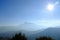 Sun flare shining on a solid blue sky on a foggy mountain landscape