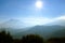 Sun flare shining on a solid blue sky on a foggy mountain landscape