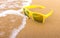 Sun glasses on sand beach with stream wave, Bubble of sea wave.