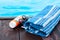 Sun glasses, tube of sunscreen cream, blue towel near swimming pool, tropical background