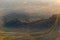 Sun glows on gondola wire lines across light and shadow, colors and clouds over expansive New Mexico landscape at sunset