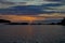 The sun goes over horizon, a beautiful sunset over the lake, clouds in the blue sky. Horizontal photo of calm nature