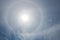 Sun halo with clouds on a blue sky, nature background. Circular Optical phenomenon