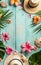 A sun hat, vibrant frangipani flowers, and starfish set on a pastel blue wooden background invoke the spirit of summer