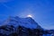 The sun hides behind the famous peak of the Eiger mountain above Grindelwald, with a lot of snow, Bern, Switzerland