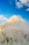 Sun Illuminated Mangart Mountains Peak in Clouds and Fog