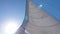 Sun light go through catamaran white sail, view on sail and mast on blu sky background