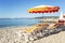 Sun loungers with orange mattresses on a sandy beach on the background of a calm blue sea. Idyll and relaxation. Space for text