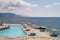 Sun loungers and parasols stand near the pool on a cobbled beach