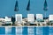 Sun loungers and umbrellas with reflection in pool water