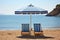 sun loungers under a parasol on a beach facing the sea