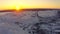 The sun peeks out from behind the mountains at dawn in the winter. Aerial view