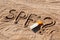 Sun protect factor. SPF word written on the sand and white bottle with suntan cream with question mark. Skin care concept