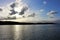 Sun rays bursting through clouds over coastal horizon