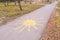 The sun with rays drawn by yellow chalk on asphalt