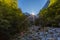 Sun, rays of light in Vikos gorge, trees, rocks, blue sky