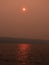 Sun rays reflect off lake through forest fire smoke