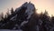 Sun Rays Shining Behind Rocky Mountain Peak Covered with Forest and Snow in Winter