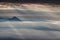 Sun rays shining through dark clouds illuminate conical peaks