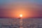 Sun rise in the ocean with a boat floating in front of the sun