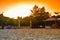 The sun rises on the beach with a pavilion on the sand.