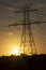 The sun rising behind a towering electricity pylon