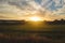 Sun rising and shining on a green rice field landscape on a cloudy sky