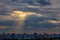 The sun`s rays break through dense clouds at dawn over the city