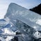 The sun\\\'s rays are refracted in crystal clear pieces of ice. winter landscape. A piece of ice and the sun on a winter lake