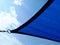 Sun sail. blue fabric sun shade material spanning over terrace area. blue sky and clouds