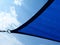 sun sail. breathing blue fabric sun shade material spanning over terrace area. blue sky and cluds