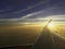 Sun set on horizon cloud sky through airplane wing