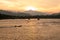 The sun sets behind the mountain, lighting up the last rays of a fishing boat, which is anchored in a tropical bay . Thailand.