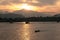 The sun sets behind the mountain, lighting up the last rays of a fishing boat, which is anchored in a tropical bay . Thailand.