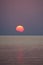 The sun sets over the horizon on the seashore. Reflection and faces on the water