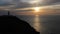 The Sun setting behind the lighthouse at Strumble Head, Pembrokeshire, Wales, UK.