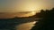 Sun setting down behind big clouds and palm trees silhouettes on ocean shore