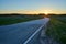 Sun setting down behind fields and empty road