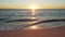 Sun setting down over the beach, calm sea waves and sand in foreground