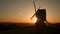 Sun setting on the horizon behind a traditional wooden windmill at sunset