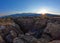 Sun setting over sierra nevada mountains with a small canyon in foreground