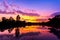 Sun setting with silhouette trees and bush around the big pond in rural of Thailand, shot taken by using long exposure therefore s