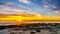 Sun setting under orange sky over the horizon of the Atlantic Ocean at Camps Bay near Cape Town